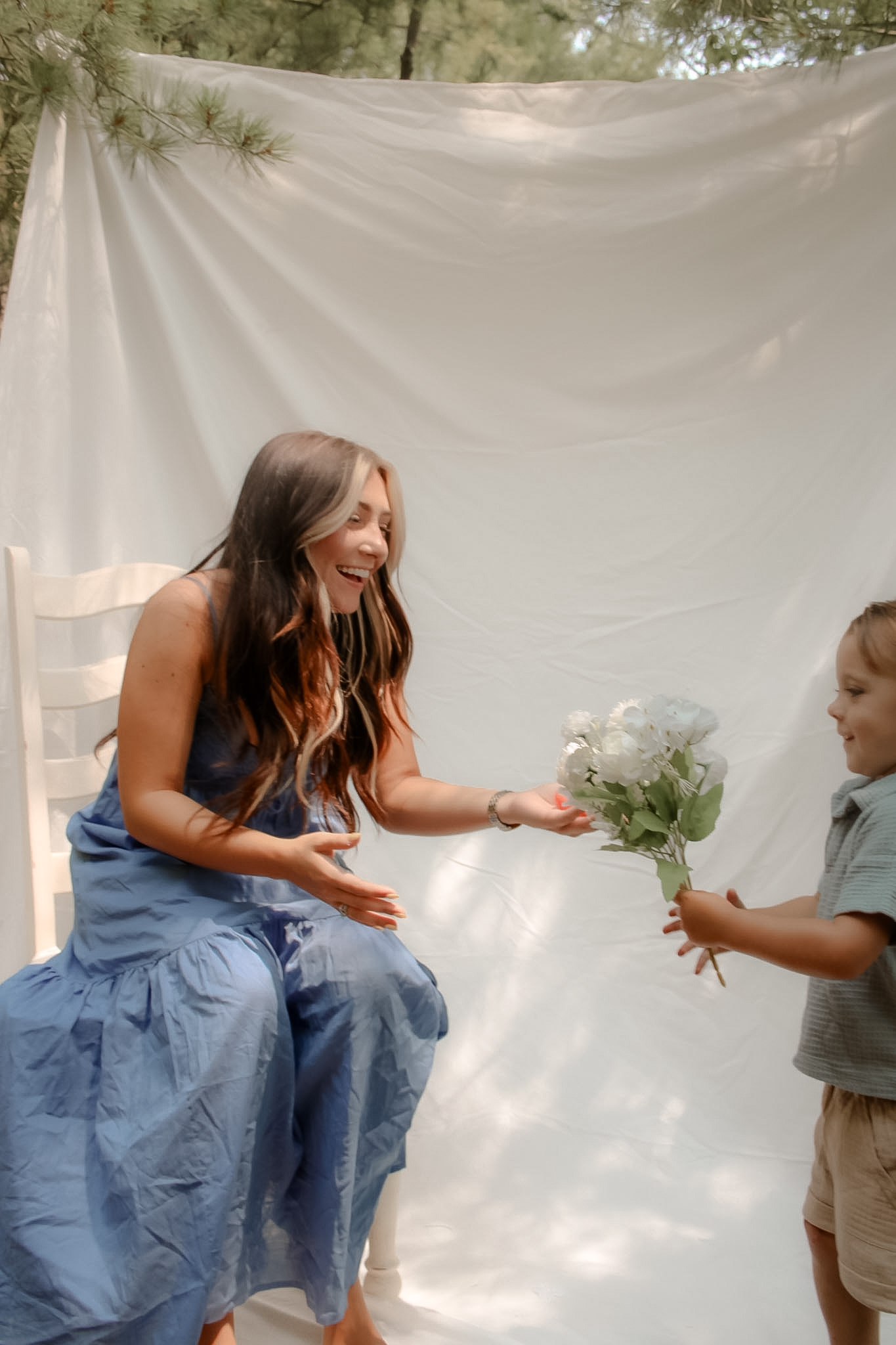 Child handing white flowers to his smiling mother