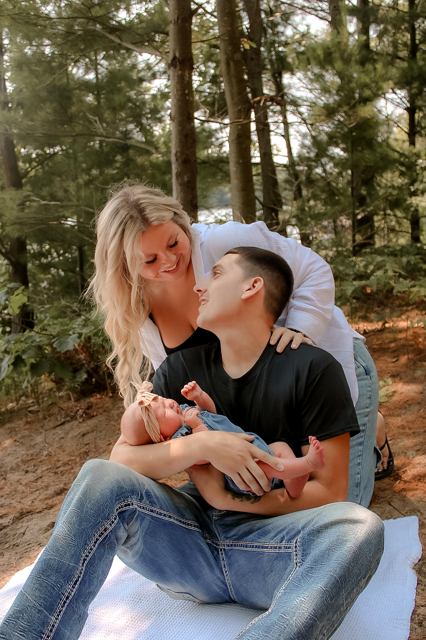 Family holding their newborn together among the trees