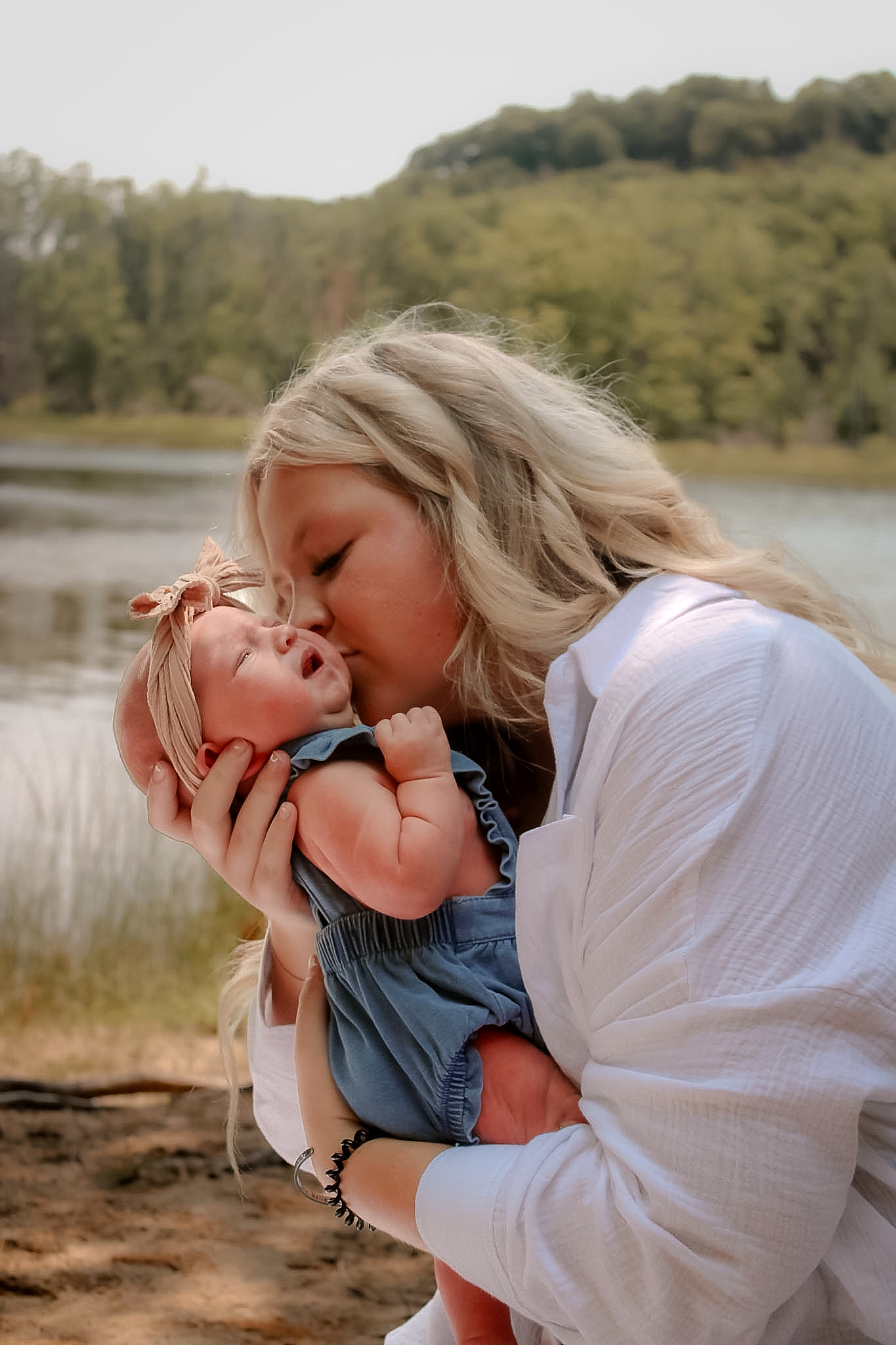 Mother kissing her newborn in warm evening light