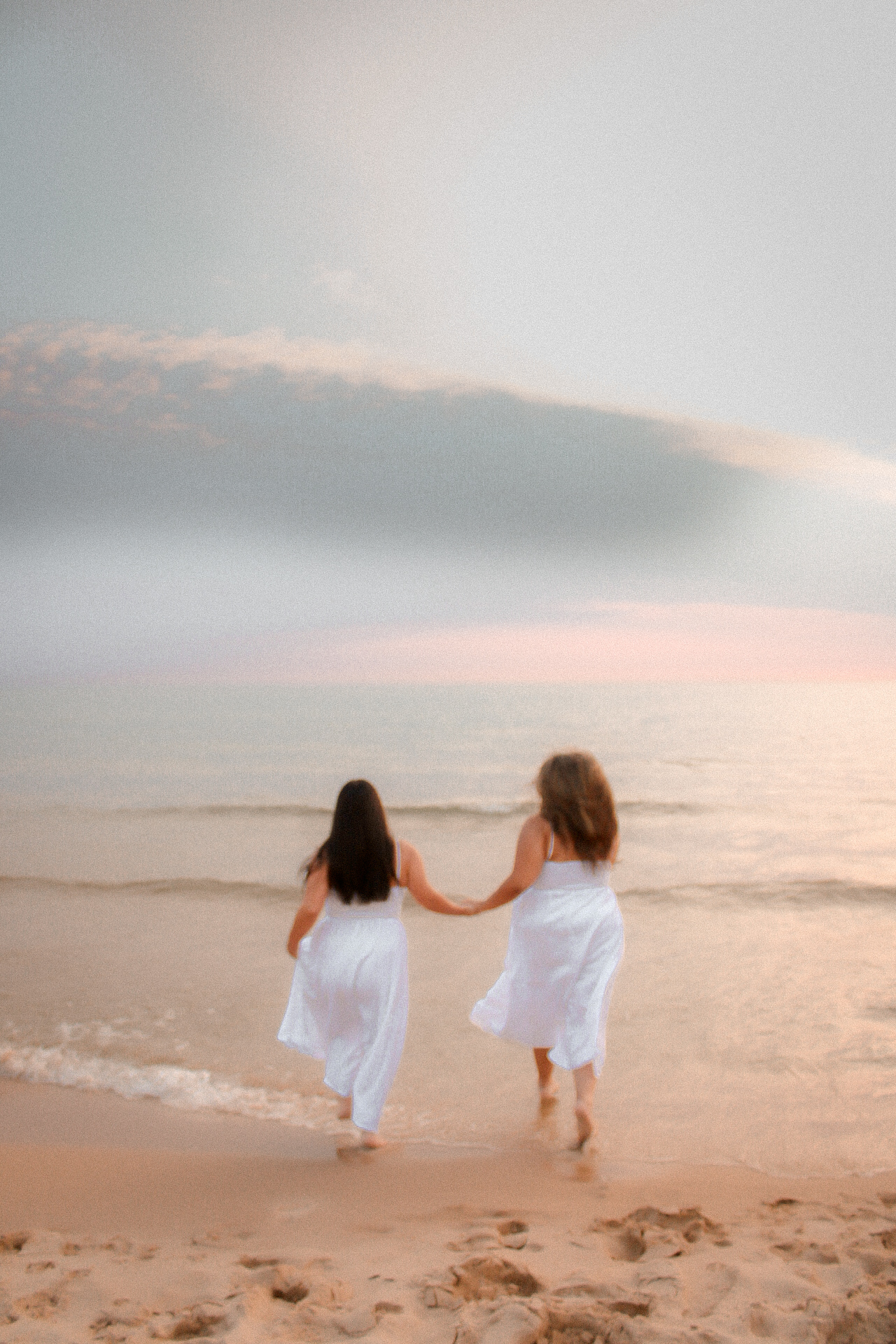 Two best friends holding hands as they run toward Lake Michigan