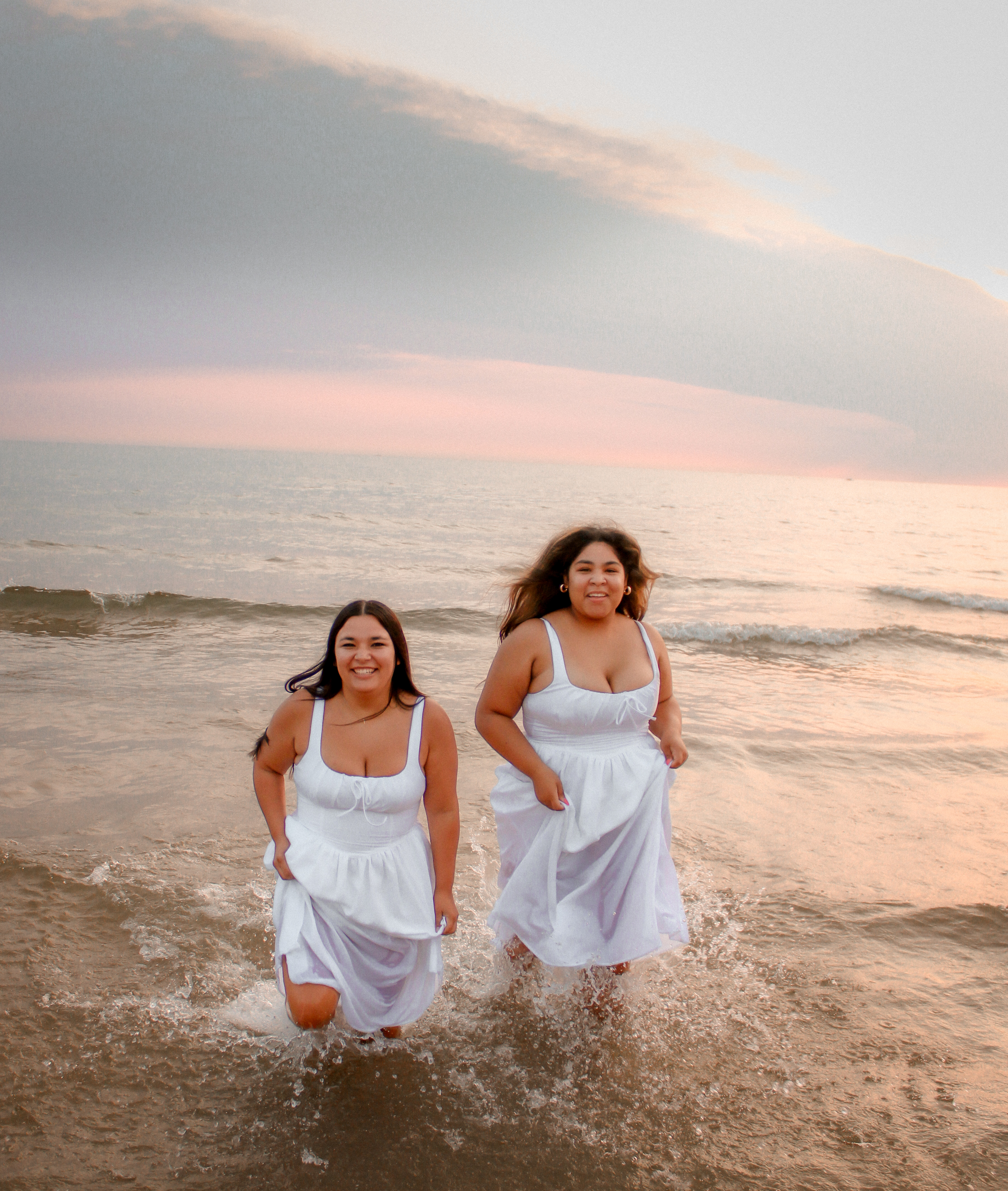Two best friends laughing as they run through shallow Lake Michigan water