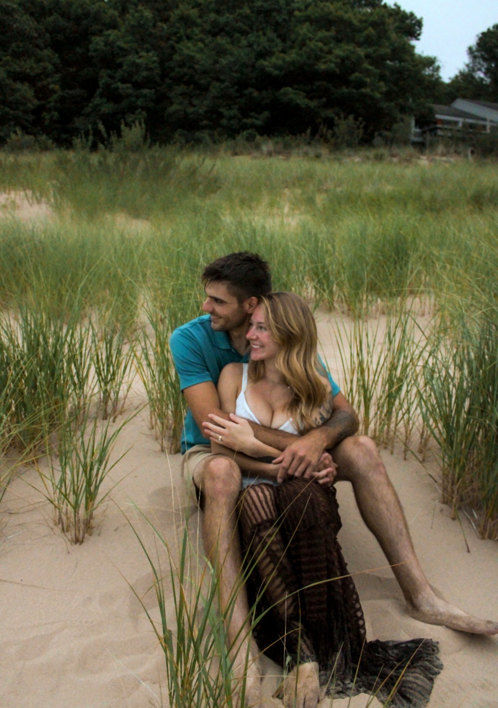 Couple seated together among beach grass and dunes