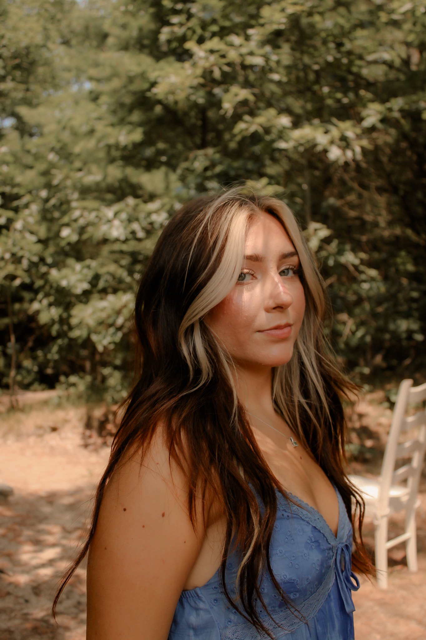 Close outdoor portrait in a blue dress beneath the trees