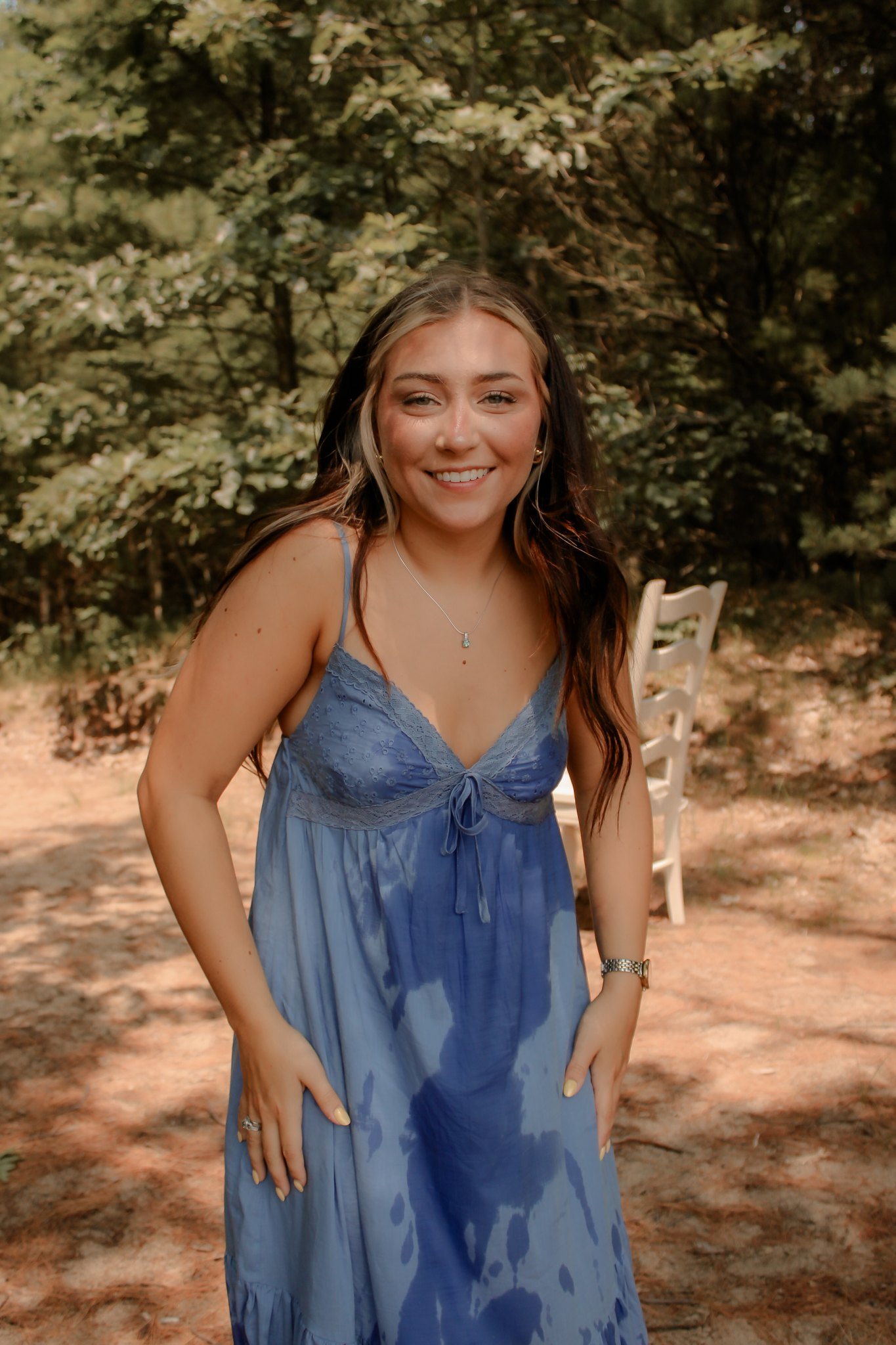 Smiling full-length outdoor portrait in a blue dress among the trees