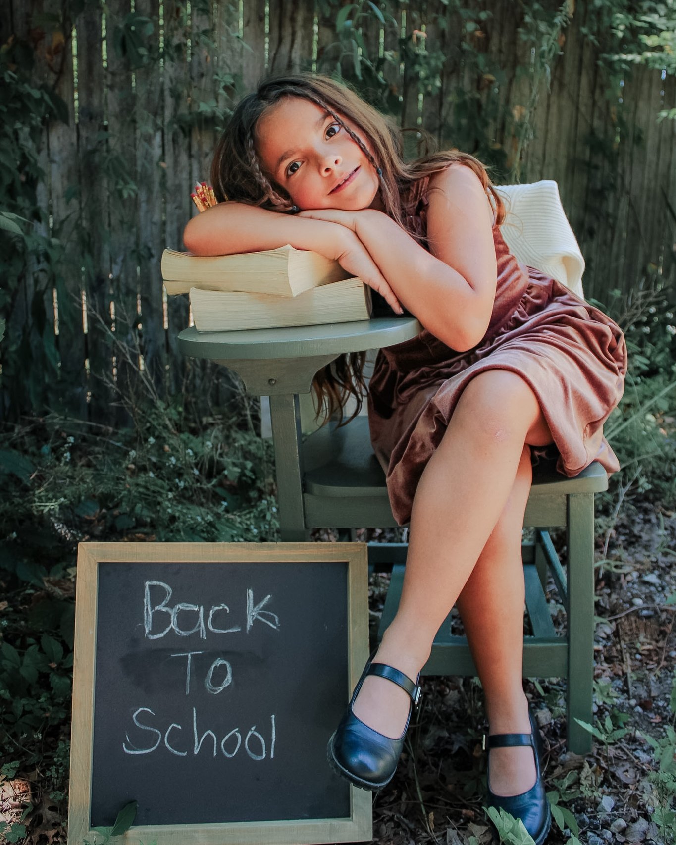 Young student resting on books beside a Back to School chalkboard